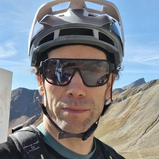 Man with bicycle helmet and sunglasses in the mountains.