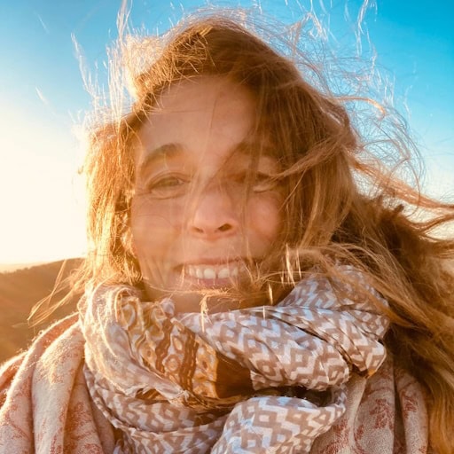 Woman smiling outdoors at sunset.