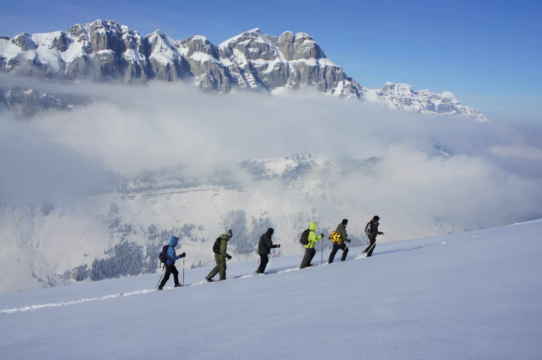 Hikers in the snow against mountain backdrop.