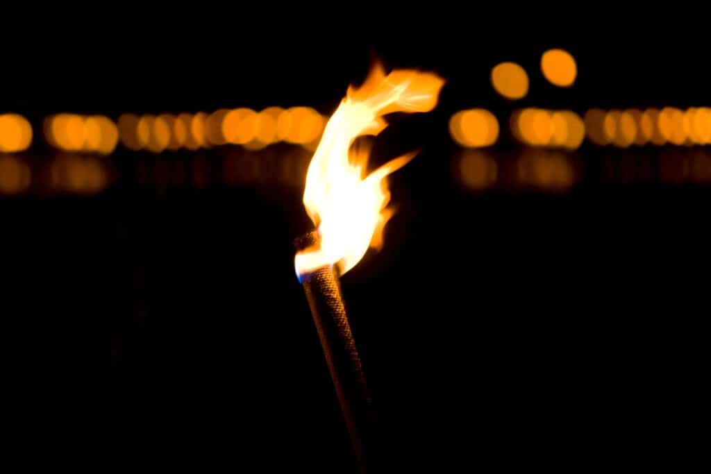 Brennende Fackel bei Nacht, unscharfer Hintergrund.