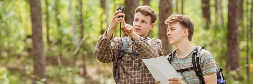 Young people hiking with compass and map.