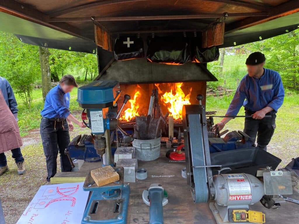 Schmiede arbeiten an Amboss mit Feuer.