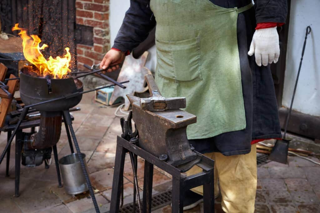 Blacksmith working on anvil with fire.