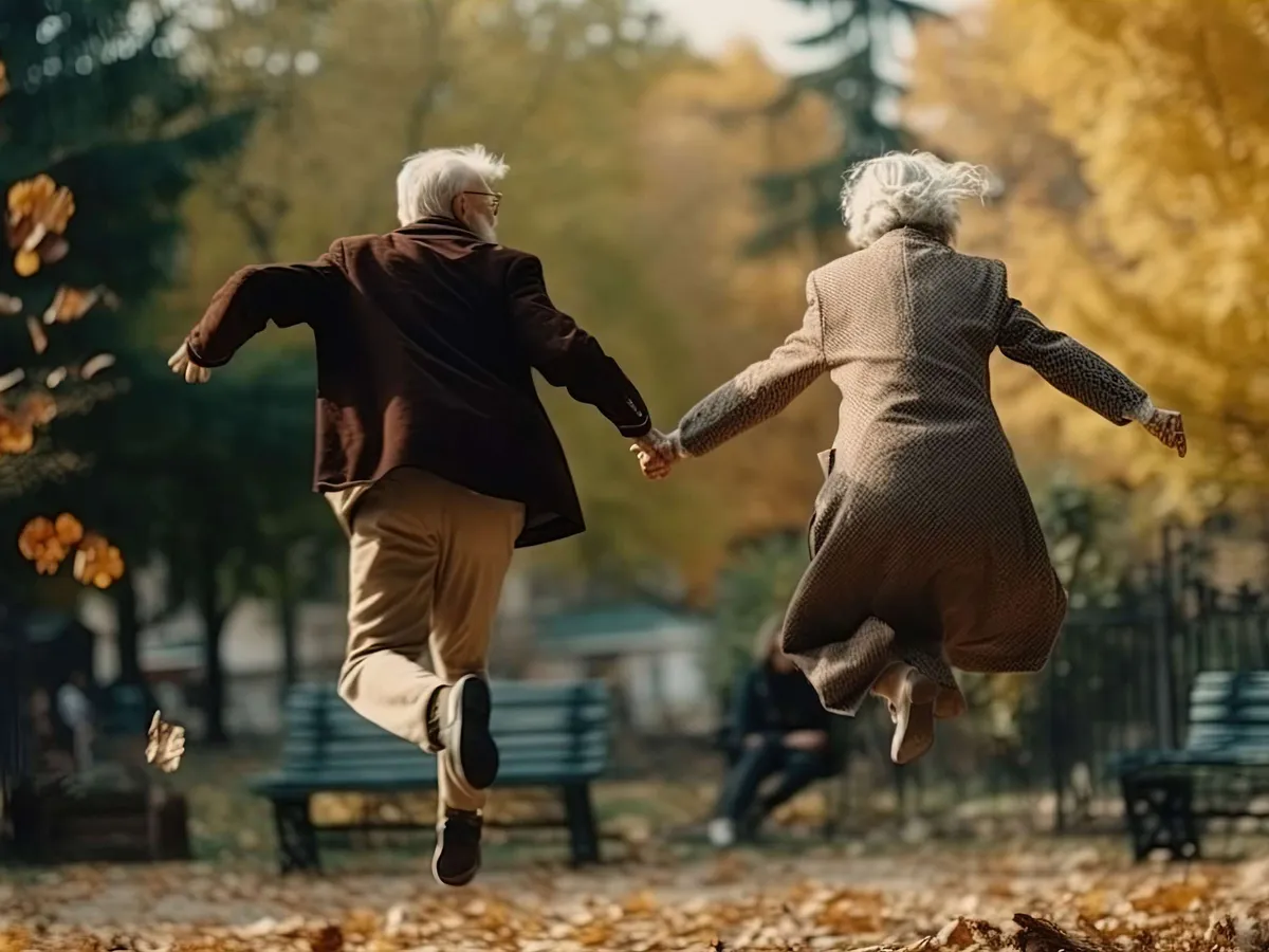 Älteres Paar springt fröhlich Hand in Hand durch einen herbstlichen Park